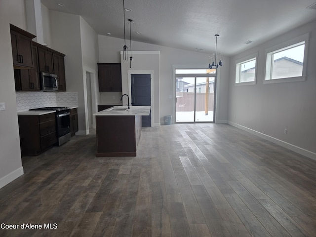 kitchen featuring a kitchen island with sink, sink, decorative light fixtures, and appliances with stainless steel finishes