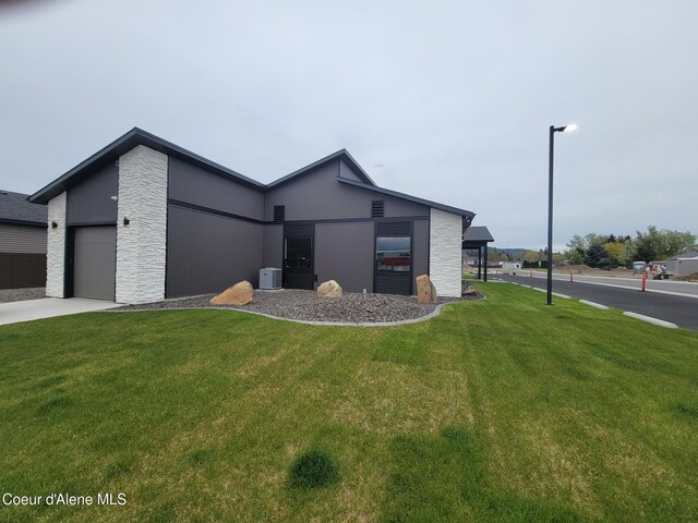 view of front of home featuring a front yard, stone siding, an attached garage, and concrete driveway