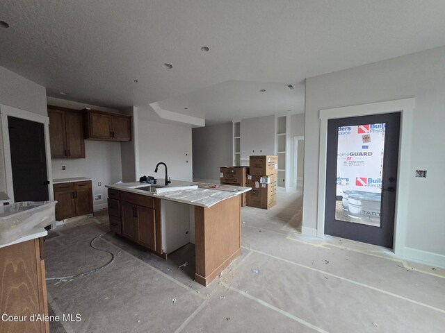 kitchen featuring a kitchen island with sink, light countertops, a sink, and open floor plan