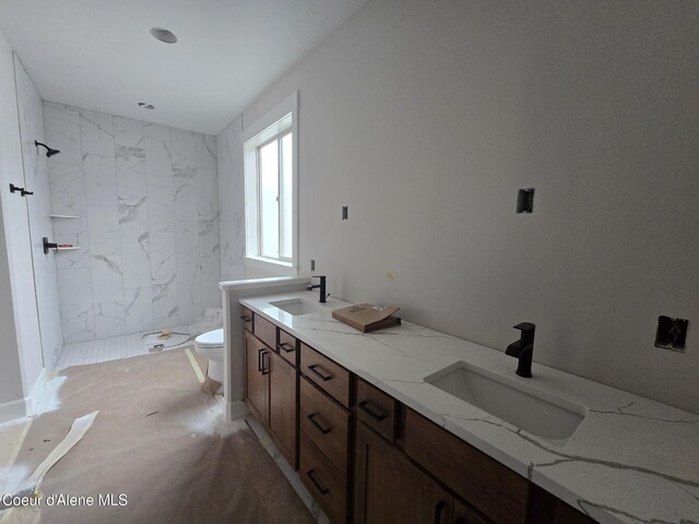 full bath featuring a sink, a tile shower, and toilet