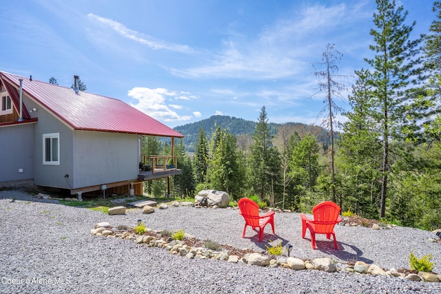 exterior space featuring a view of trees, a deck with mountain view, and an outdoor fire pit