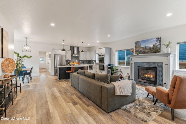 living room with light hardwood / wood-style flooring, a notable chandelier, and a tiled fireplace