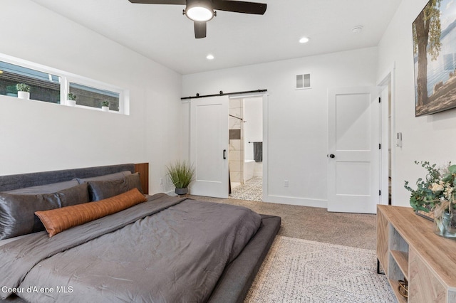 carpeted bedroom featuring connected bathroom, a barn door, and ceiling fan