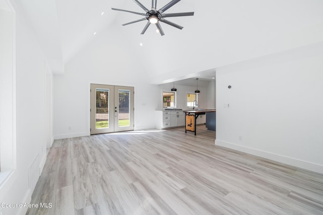 unfurnished living room with ceiling fan, light hardwood / wood-style floors, high vaulted ceiling, and french doors