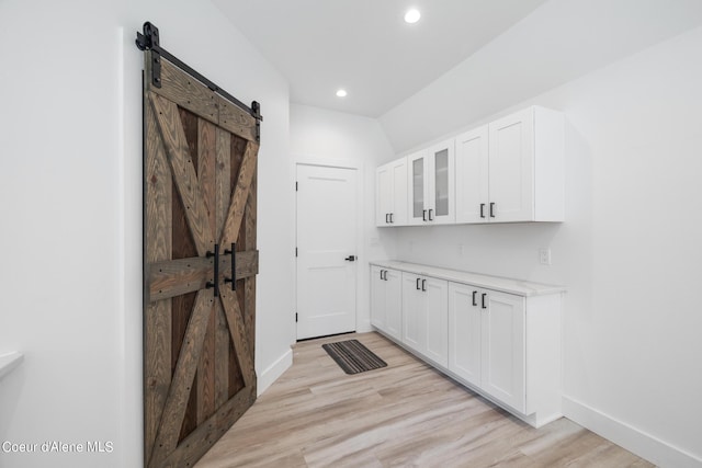 laundry area with a barn door and light hardwood / wood-style floors