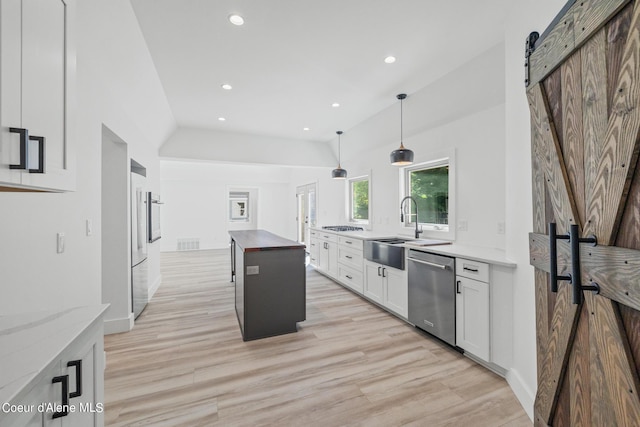 kitchen with white cabinetry, a center island, a barn door, decorative light fixtures, and appliances with stainless steel finishes