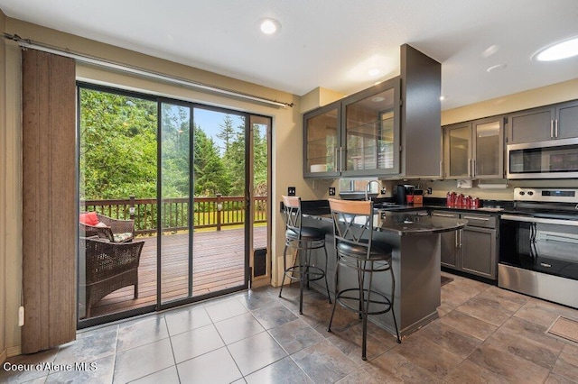 kitchen with sink, kitchen peninsula, appliances with stainless steel finishes, and a kitchen breakfast bar