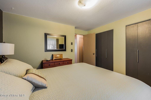 bedroom with multiple closets and a textured ceiling