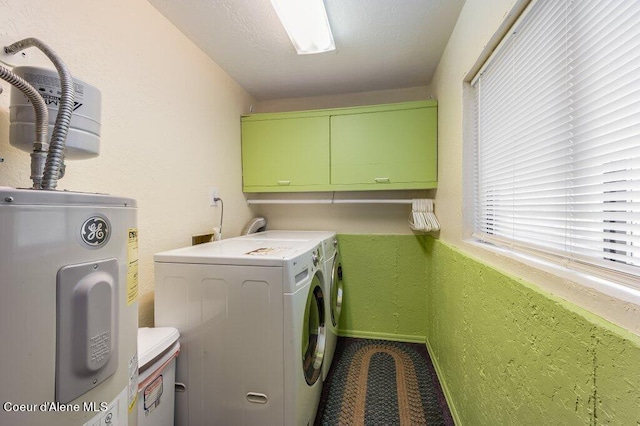 clothes washing area featuring cabinets, electric water heater, and washing machine and clothes dryer