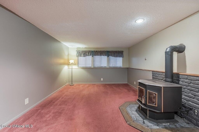 living room featuring a wood stove, a textured ceiling, and carpet flooring