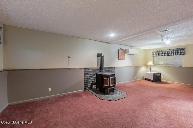 basement with a wood stove, carpet, and a textured ceiling