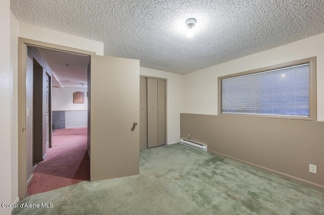 interior space with light colored carpet, a textured ceiling, a baseboard heating unit, and a closet