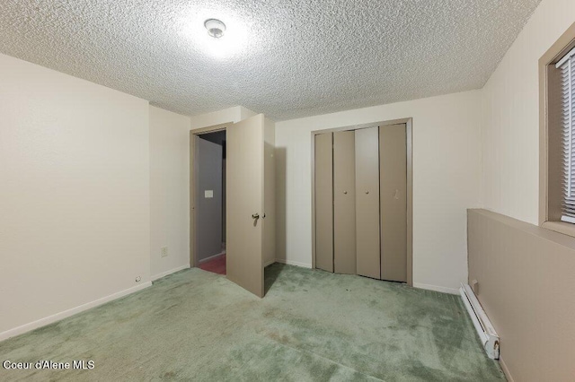 unfurnished bedroom featuring a textured ceiling, a baseboard heating unit, a closet, and light carpet