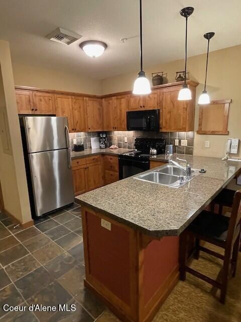 kitchen featuring black appliances, pendant lighting, kitchen peninsula, and sink