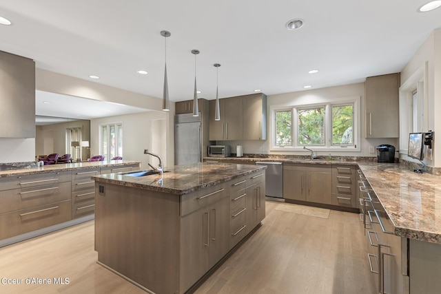 kitchen featuring sink, a kitchen island, decorative light fixtures, and appliances with stainless steel finishes