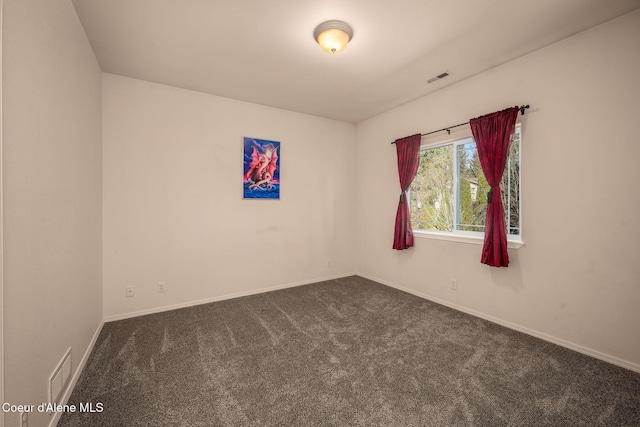 unfurnished room with visible vents, baseboards, and dark carpet