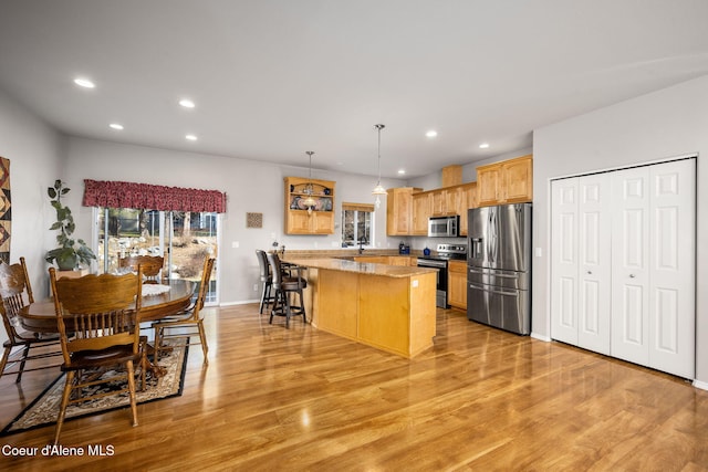 kitchen with recessed lighting, stainless steel appliances, pendant lighting, a kitchen breakfast bar, and light wood-type flooring