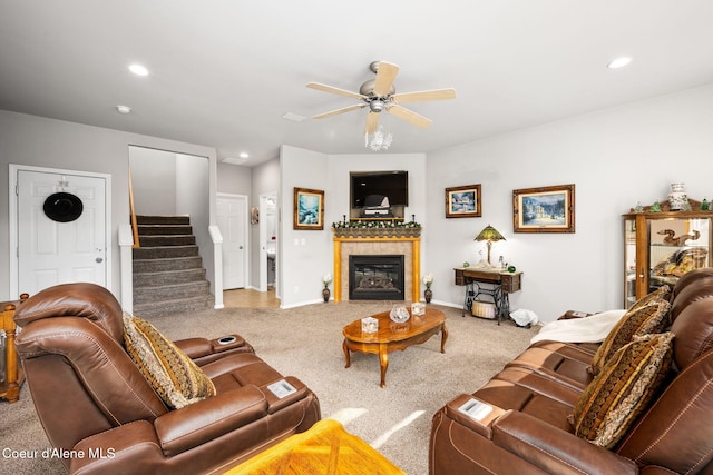 carpeted living area with baseboards, stairway, recessed lighting, a fireplace, and a ceiling fan