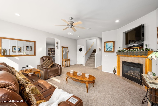 carpeted living room with ceiling fan, stairway, recessed lighting, a fireplace, and arched walkways