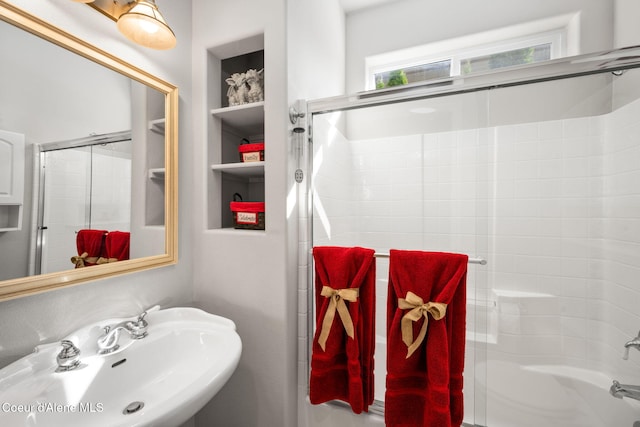 bathroom with a sink, built in shelves, and shower / bath combination with glass door