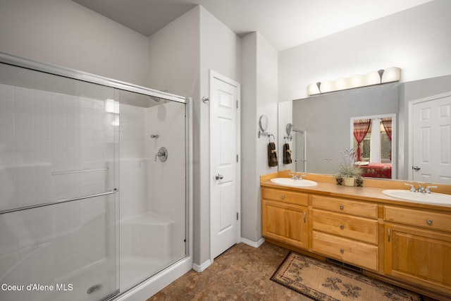 bathroom featuring double vanity, a shower stall, and a sink