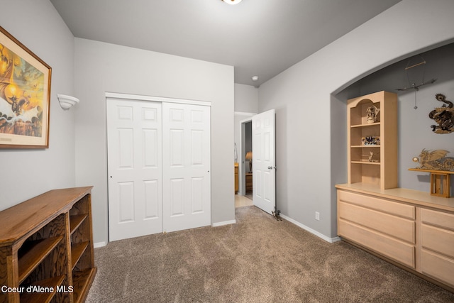 unfurnished bedroom with a closet, arched walkways, baseboards, and carpet