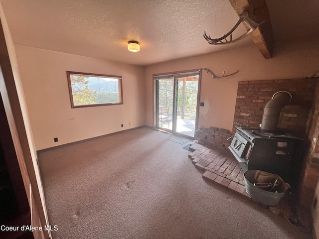 unfurnished living room with a wood stove and a textured ceiling