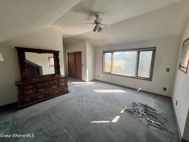 unfurnished bedroom with ceiling fan, a textured ceiling, carpet, and vaulted ceiling