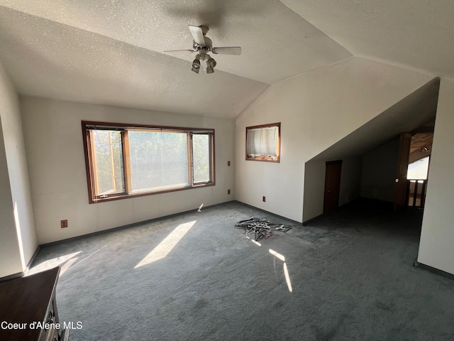 unfurnished living room with ceiling fan, dark colored carpet, a textured ceiling, and lofted ceiling