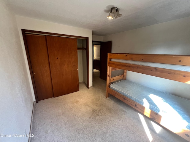 unfurnished bedroom with a textured ceiling, light colored carpet, and a closet