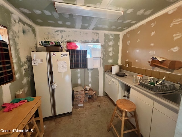 kitchen featuring sink, white cabinetry, and white fridge