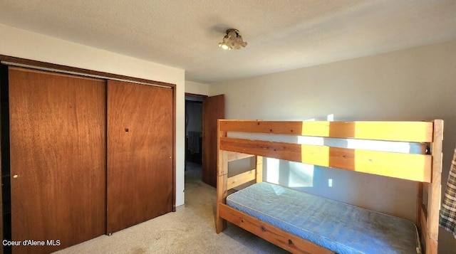 bedroom featuring a textured ceiling, a closet, and light carpet