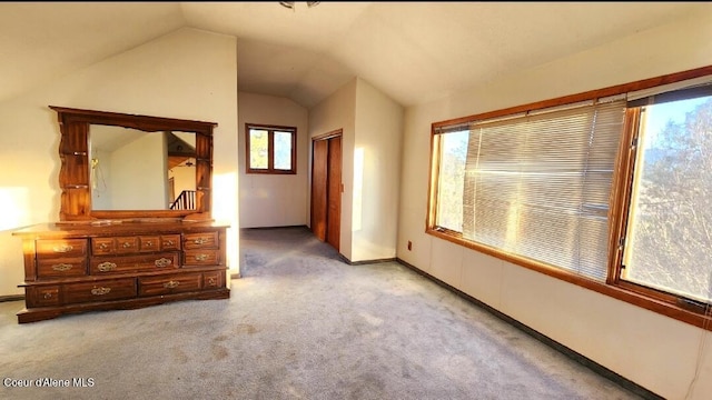 interior space with multiple windows, light carpet, and lofted ceiling