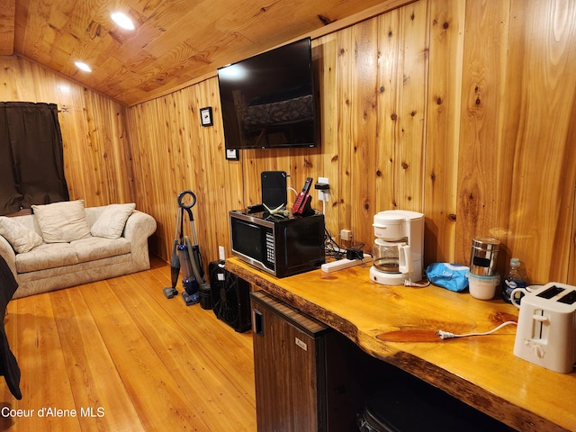 living room featuring lofted ceiling, light hardwood / wood-style floors, wooden ceiling, and wooden walls