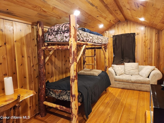 bedroom featuring light wood-type flooring, wooden ceiling, wooden walls, and vaulted ceiling