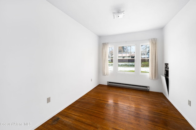 spare room with baseboard heating and dark wood-type flooring