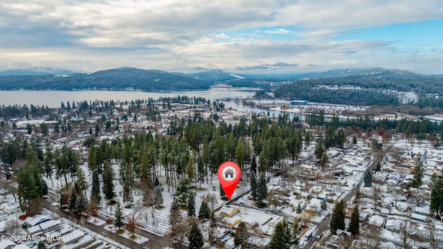 snowy aerial view featuring a water and mountain view