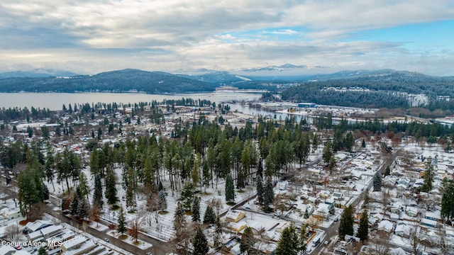 snowy aerial view featuring a water and mountain view