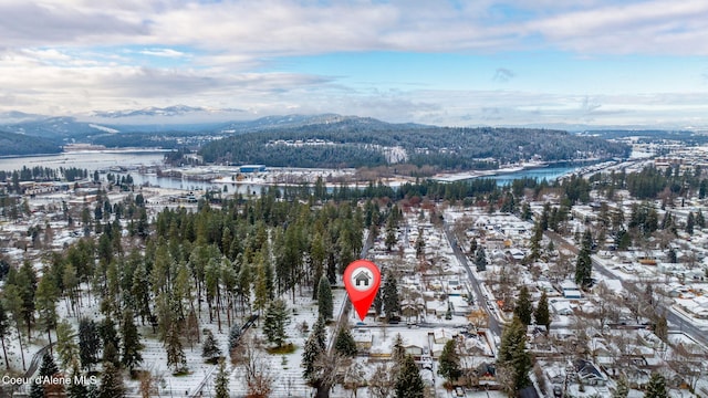 snowy aerial view featuring a water and mountain view