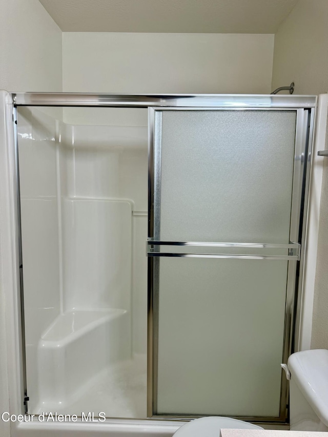 bathroom with toilet and a shower with door