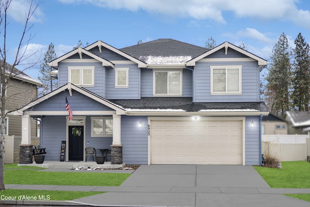 craftsman-style house with covered porch, a shingled roof, an attached garage, and fence