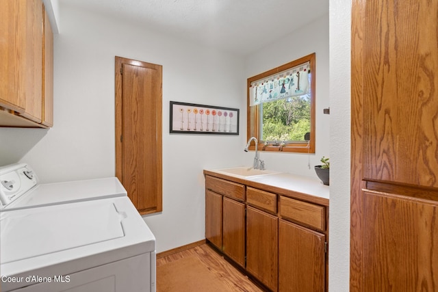 clothes washing area with washer and dryer, sink, and cabinets