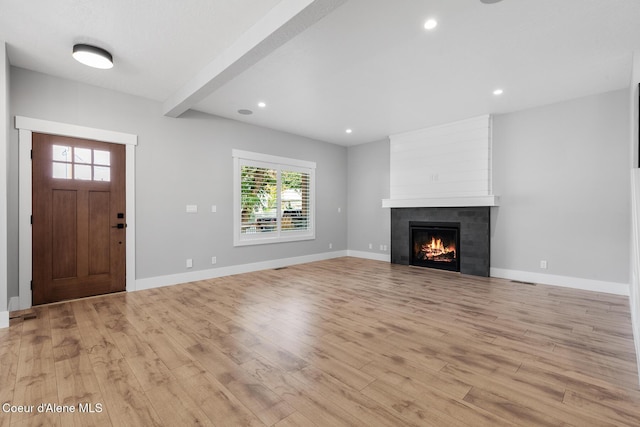 unfurnished living room with a fireplace, light hardwood / wood-style floors, and beamed ceiling