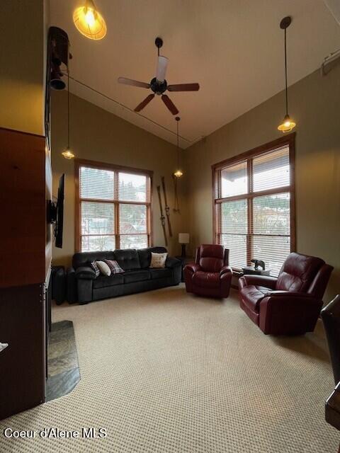 carpeted living room with vaulted ceiling, ceiling fan, and plenty of natural light