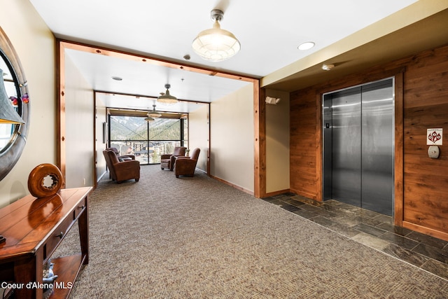 interior space with elevator, wooden walls, and dark colored carpet