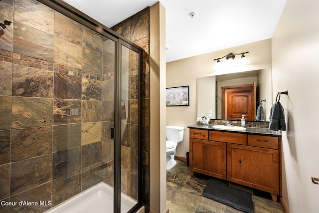 bathroom featuring a shower with door, vanity, and toilet