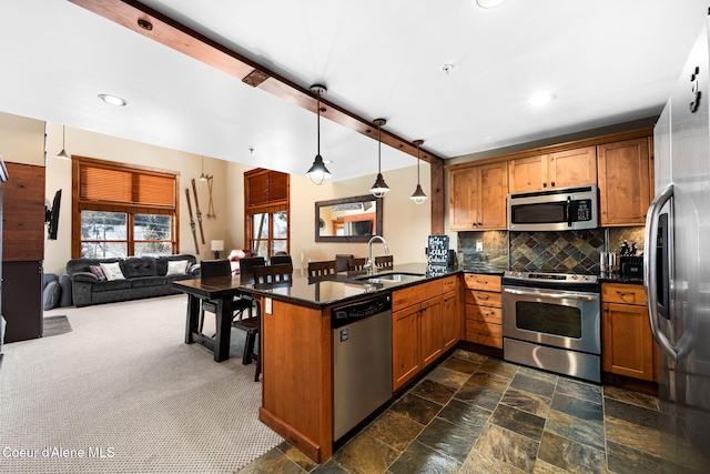 kitchen with appliances with stainless steel finishes, pendant lighting, sink, decorative backsplash, and kitchen peninsula