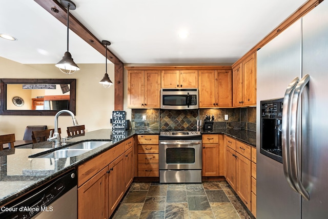 kitchen featuring appliances with stainless steel finishes, pendant lighting, sink, backsplash, and dark stone counters