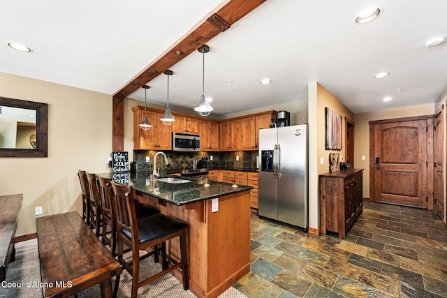 kitchen with pendant lighting, sink, stainless steel appliances, tasteful backsplash, and kitchen peninsula