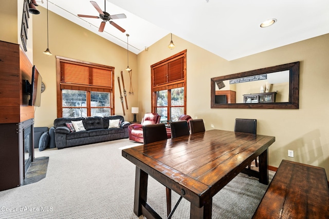 carpeted dining room with ceiling fan and high vaulted ceiling